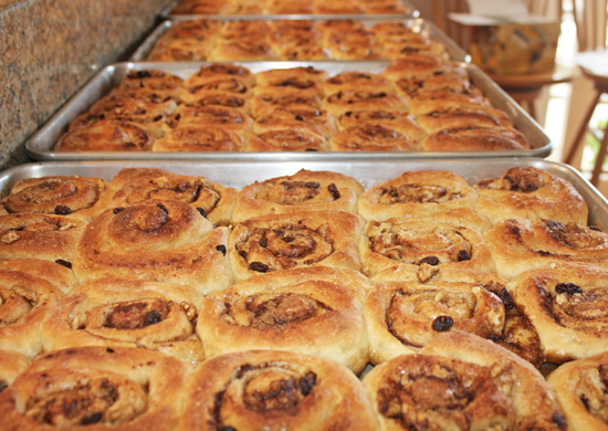 Four trays of Cinnamon Rolls ready to be served after a Sunday church service.