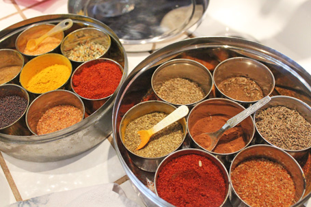 Cooking with Indian spices like turmeric, red pepper, cumin seeds and cardamom. 