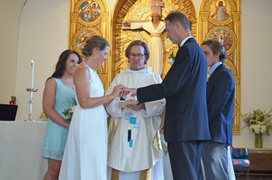 Father Peter Rood of Holy Nativity Episcopal Church blesses the wedding rings.  Photo by Mike Gitchell.