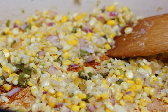 Onion and corn are cooked together in a skillet. Garlic and minced jalapeno are added at the end of cooking.